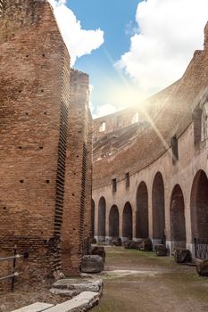 Close up detailed inside view of ancient amphitheatre of Colosseum built by Vespasian and Titus in Rome, on cloudy blue sky background.