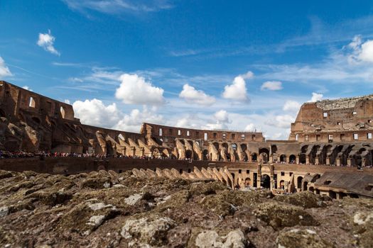 ROME, ITALY - SEPTEMBER 24, 2015 : Inside view of ancient amphitheatre of Colosseum built by Vespasian and Titus in Rome, on cloudy blue sky background.