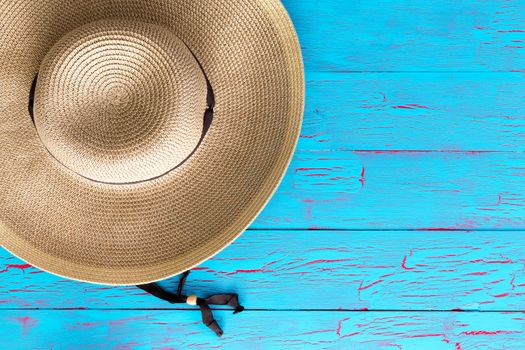 Wide brimmed straw gardening hat on an old weathered colorful blue picnic table with copy space in an overhead view