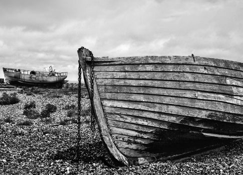 An old abandoned fishing boat stranded on a beech in black and white.