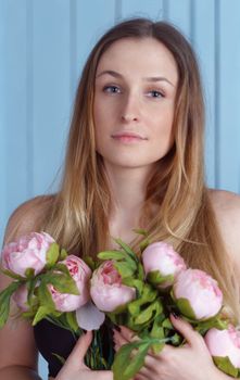 Beautiful close-up portrait of a young woman with peonies wreath. Spring natural care concept.