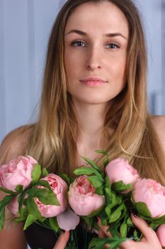 Beautiful close-up portrait of a young woman with peonies wreath. Spring natural care concept.