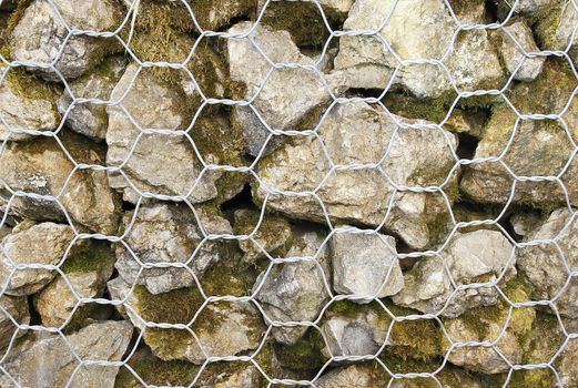 Closeup of a barrier built of small pieces of rock behind a fence of metallic mesh in thailand