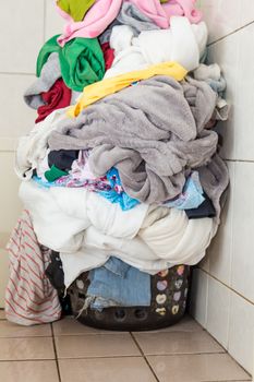 Laundr basket overflowing with dirty clothes and blankets