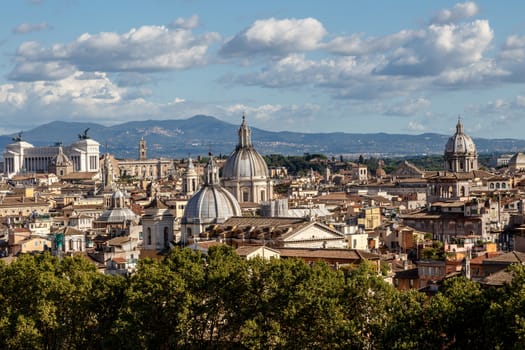 Top view of historical city of Rome with domes, on cloudy blue sky background.