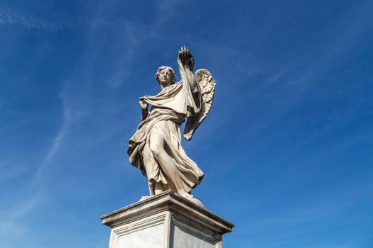 Close up detailed bottom view of a granit woman sculpture with wings, on bright blue sky background.