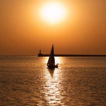 Sail boat against sea sunset. Colorful marine landscape.