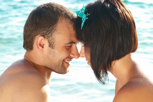 Love couple on the beach against water backdround