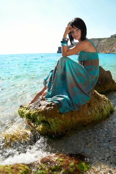 Pretty woman in dress on the sea rock