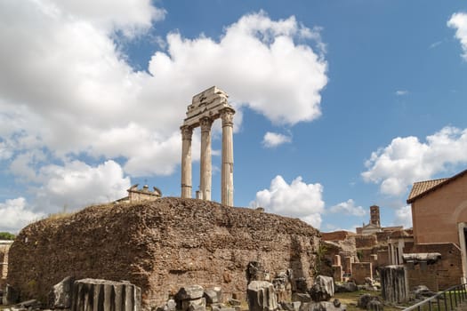 View of archeological area of ancient Roman Forum in Rome, on cloudy blue sky background.