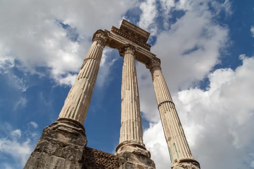 View of archeological area of ancient Roman Forum in Rome, on cloudy blue sky background.