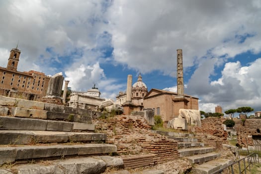 View of archeological area of ancient Roman Forum in Rome, on cloudy blue sky background.