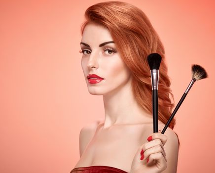 Beauty portrait nude woman eyelashes, perfect skin, red lips, fashion. Gorgeous sensual attractive pretty redhead sexy model girl with makeup brushes on pink, shiny wavy hair. People face, copyspace