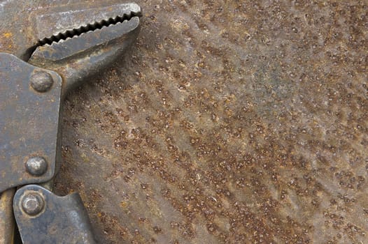 Old pipe wrench on rusty metal background