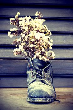 Old ruined boot is used as a vase for wild flowers - vintage stylized photo