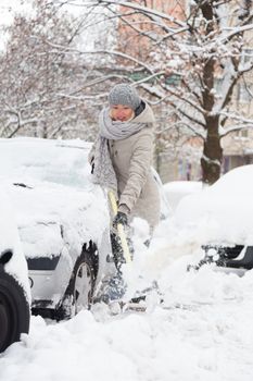 Independent woman shoveling her parking lot after a winter snowstorm.