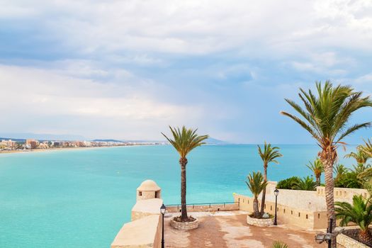 Turquoise sea and palm trees of Peniscola, the resort in the province of Castellon, Valencian Community, Spain.