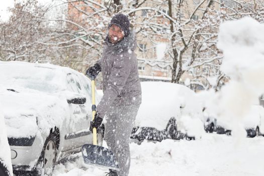 Man shoveling her parking lot after a winter snowstorm.