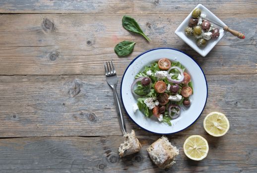 Greek salad with kalamata olives and feta cheese on top of a wooden table with space