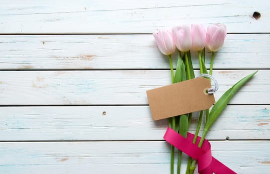 Pink tulips on a wooden background wtih gift tag