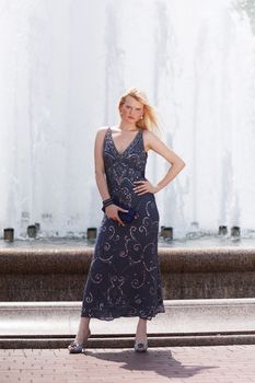 Blond woman in glitter dress next to fountain