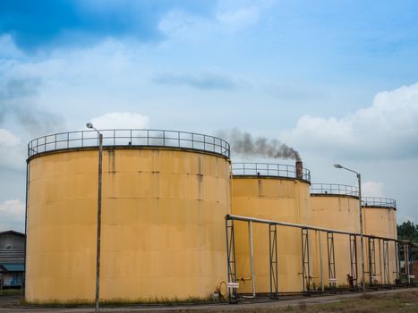 Metal oil tanks in Palm oil refinery plant and puffs of smoke, Thailand.