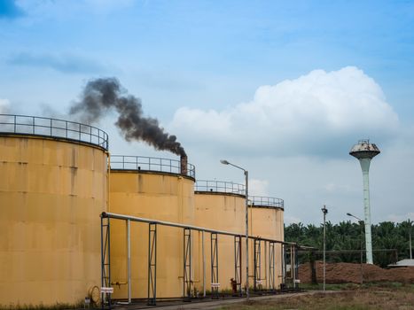 Metal oil tanks in Palm oil refinery plant and puffs of smoke, Thailand.