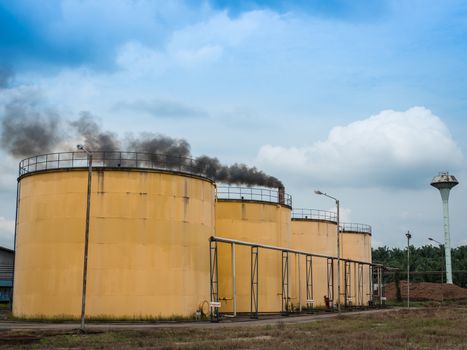 Metal oil tanks in Palm oil refinery plant and puffs of smoke, Thailand.