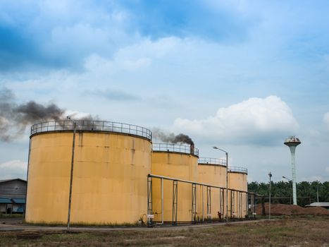 Metal oil tanks in Palm oil refinery plant and puffs of smoke, Thailand.