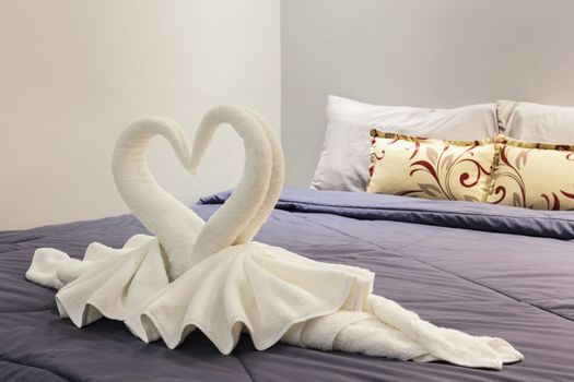 towel folded in swan shape on bed sheet