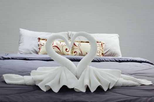 towel folded in swan shape on bed sheet