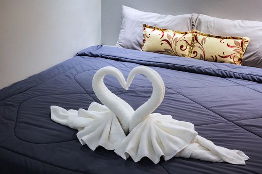 towel folded in swan shape on bed sheet