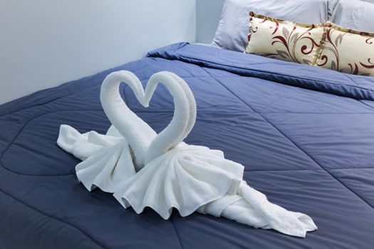 towel folded in swan shape on bed sheet