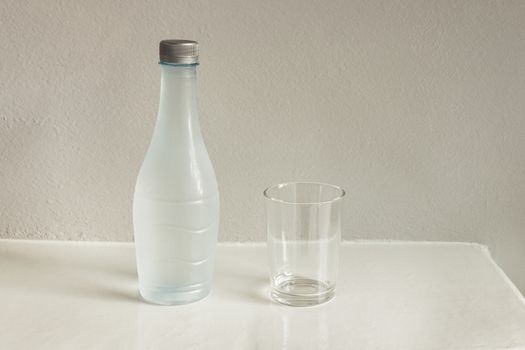 bottle of water and glass on white table