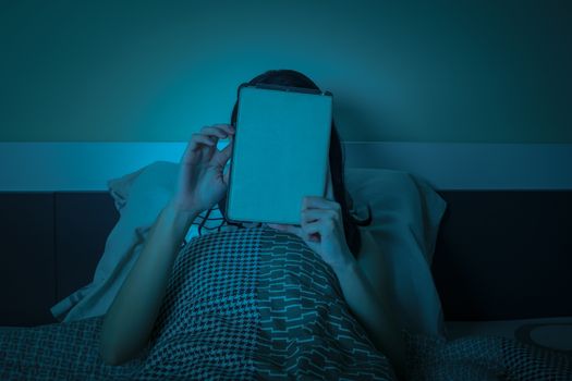 Woman work with tablet or computer on the bed at night