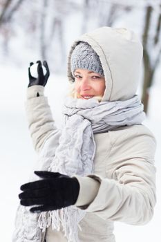 Cute casual young woman snowball fighting in winter time.