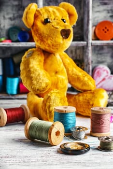 Made by hand toy bear on the background of tools for needlework