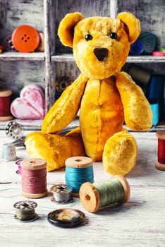 Made by hand toy bear on the background of tools for needlework