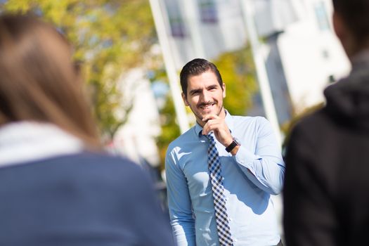 Attractive young businessman with a friendly smile having informal out of office meeting on a suny day.