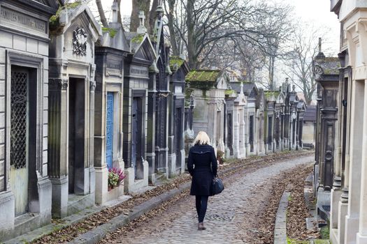 Solitary woman remembering dead relatives in on Pere Lachaise cemetery in Paris, France.