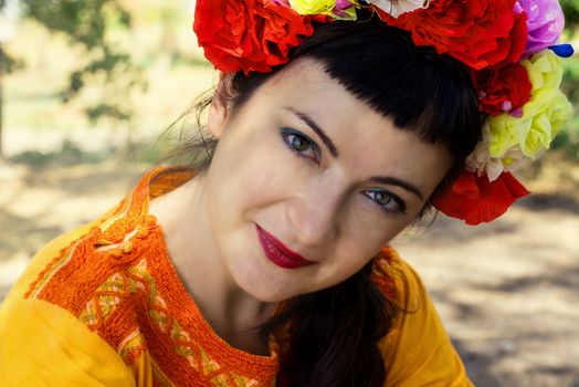 charming woman in wreath of roses on her head on the background of nature