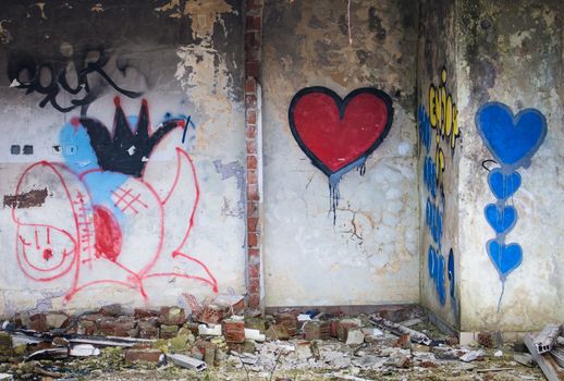 Red and blue hearts graffiti painted on the wall in an abandoned building.