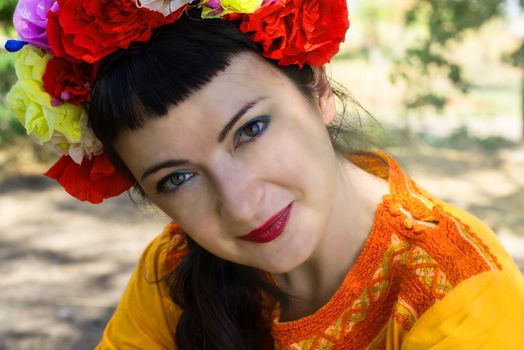 charming woman in wreath of roses on her head on the background of nature