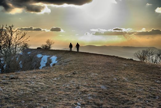 Couple on the hill against sunset. Landscape with clouds and sky.