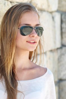 Beautiful blond girl in the goggles against the ancient wall