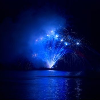 Blue colorful fireworks on the black sky background. Holiday celebration.