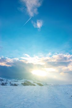 Winter hills covered by snow against sunset