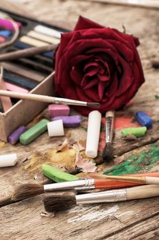 Crayons and paints for painting on wooden background