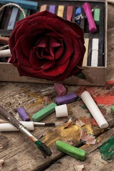 Crayons and paints for painting on wooden background