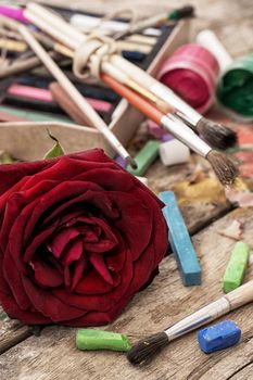 Crayons and paints for painting on wooden background